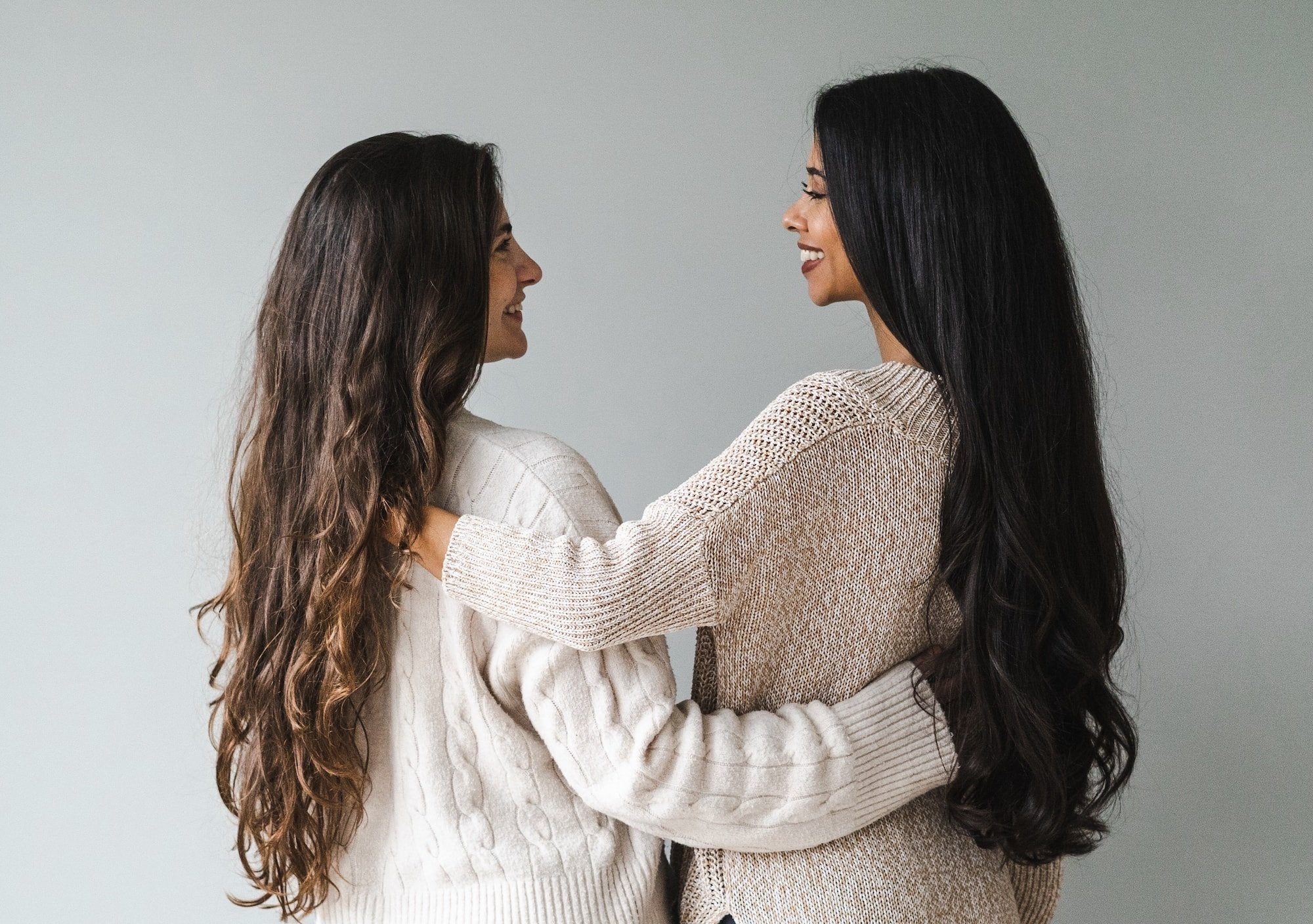 Two women hugging each other against a plain background