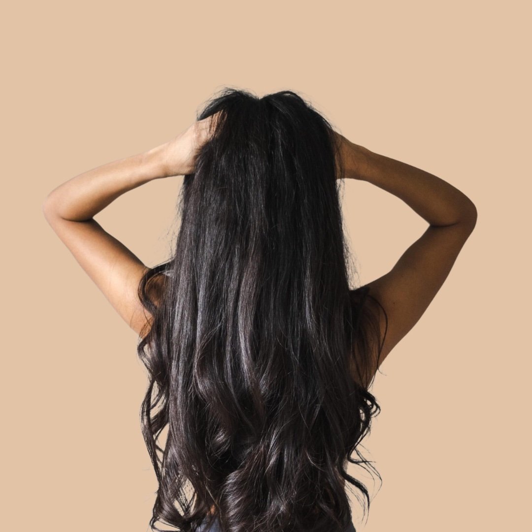 Person with long, wavy hair against a beige background